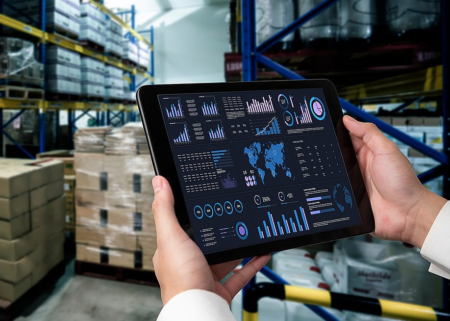 A business data dashboard in an iPad is shown and held by a marketing officer in a stock room. — Summit Art Creations // Shutterstock