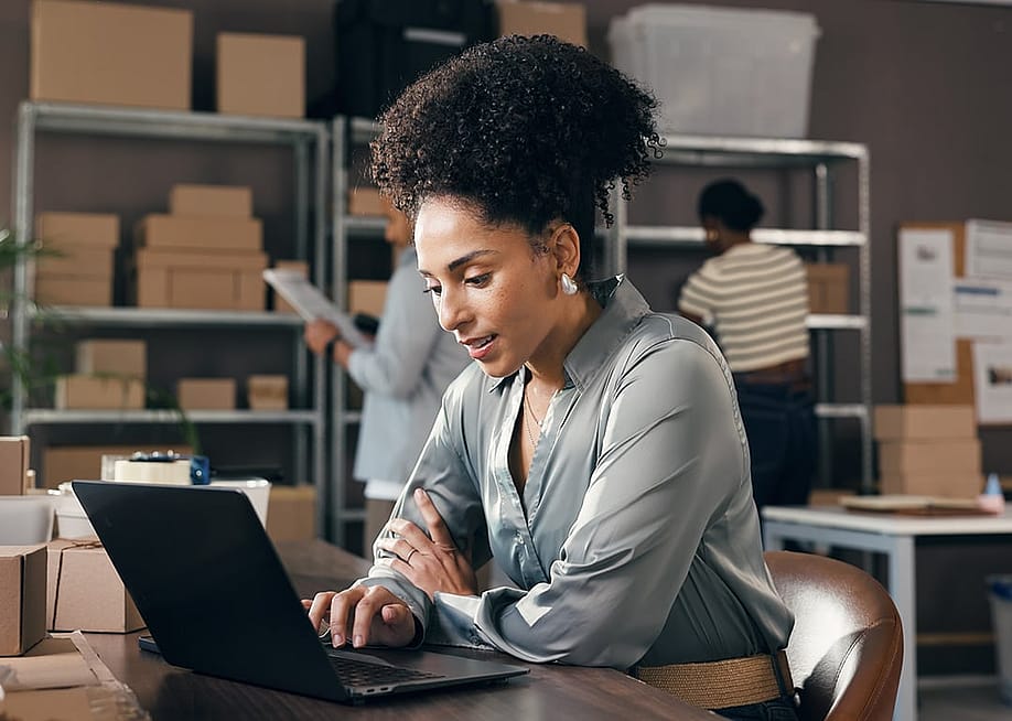 A female businesswoman working with a laptop at a logistics warehouse. — PeopleImages // Shutterstock