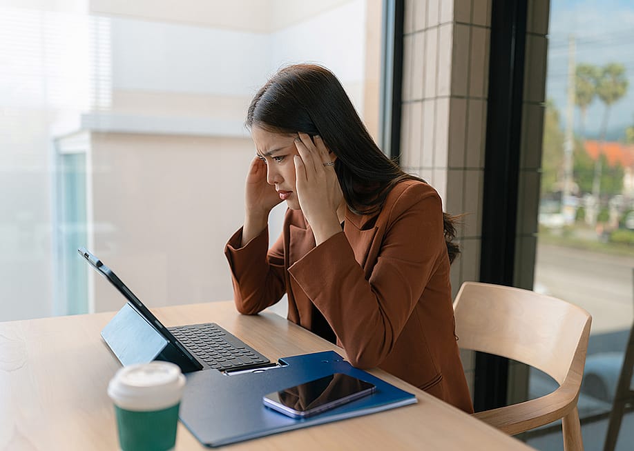 A woman employee who appears to be stressed sits in her workplace desk. — THICHA SATAPITANON // Shutterstock