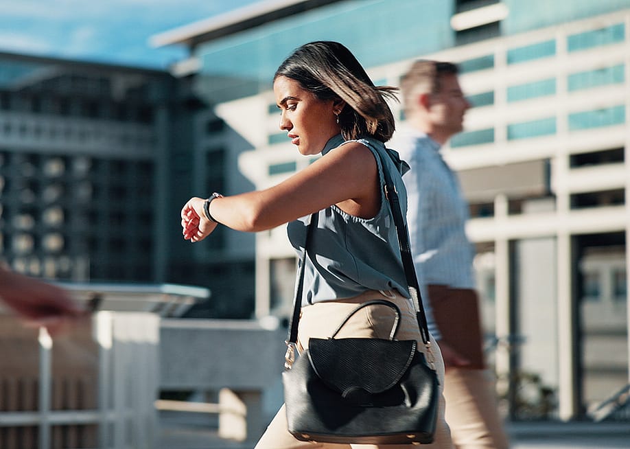 A woman on the way to work checking the time on her watch. — PeopleImages // Shutterstock