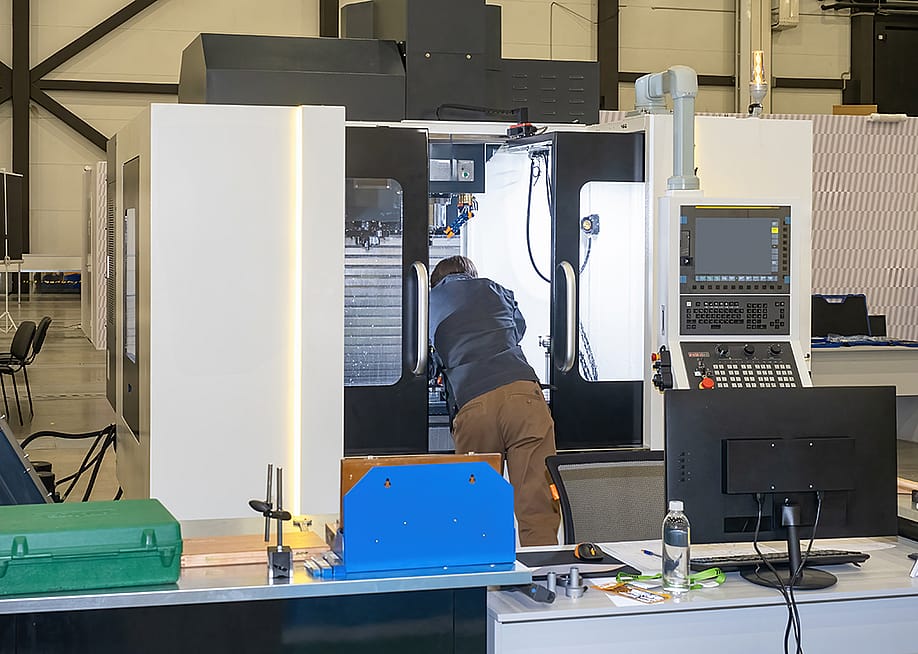 A man looking inside a CNC machine during a maintenance process in a production workshop. — FOTOGRIN // Shutterstock