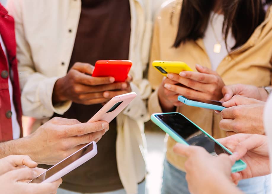 A group of young people using smartphone forming a circle outdoors. — Xavier Lorenzo // Shutterstock