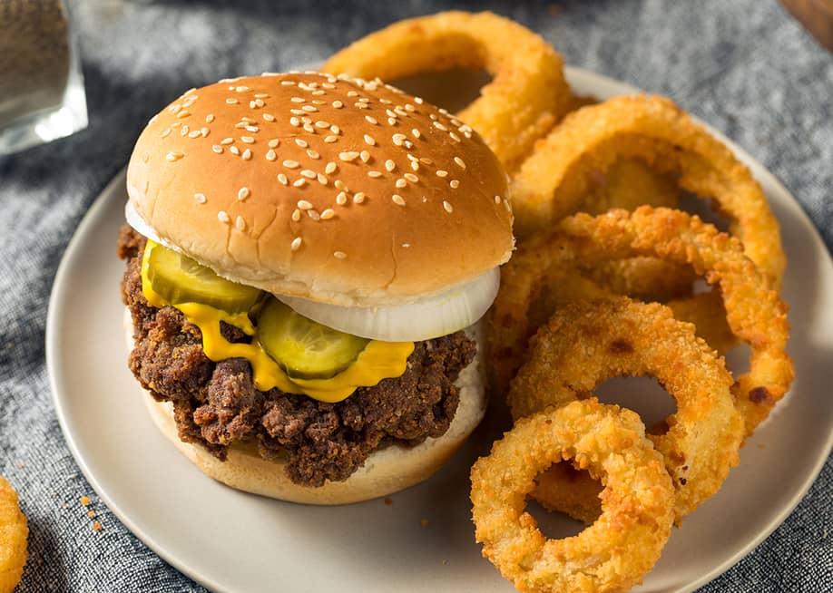 Homemade slug burgers with pickles and onion rings on the side. — Brent Hofacker // Shutterstock