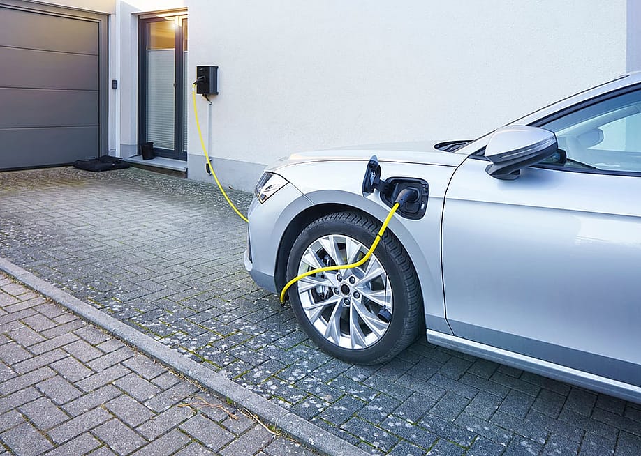 A car connected to an EV charger at home installed in the driveway. — Gordine N // Shutterstock