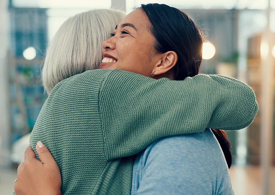 A smiling female staff member sharing a hug with an elderly woman in a physiotherapy place. — PeopleImages // Shutterstock