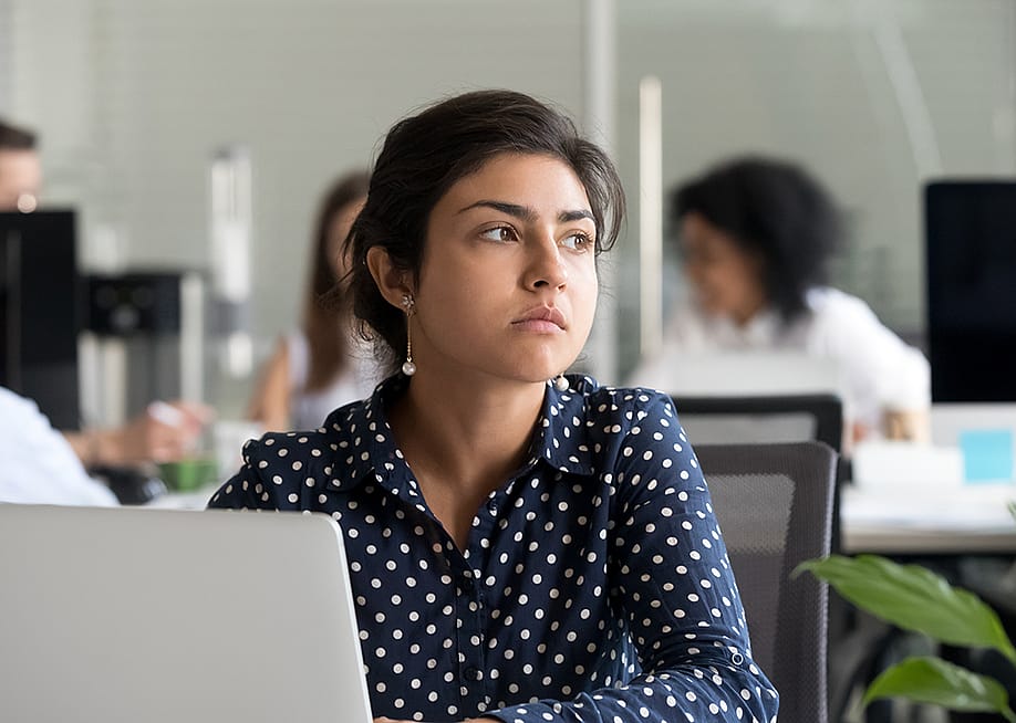 An employee looking away from a laptop in the office. — fizkes // Shutterstock