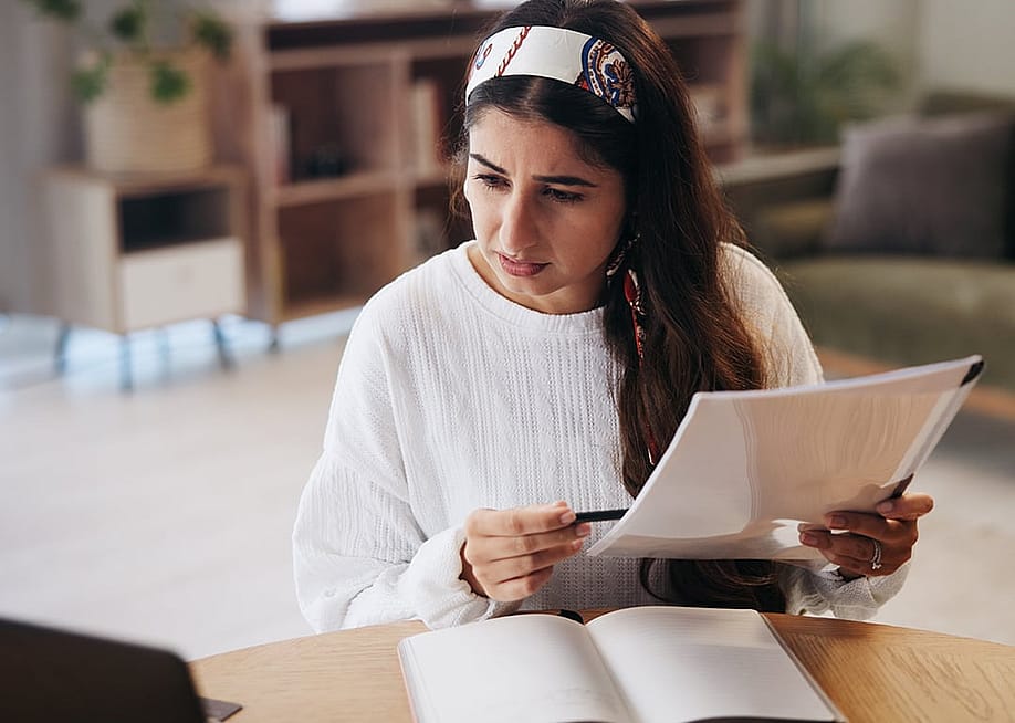 A person going through paperwork at home. — PeopleImages // Shutterstock