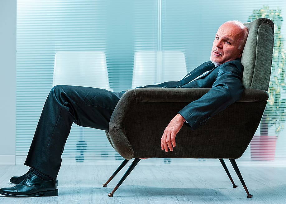An elderly business person slouching in a chair at an office. — Giulio_Fornasar // Shutterstock