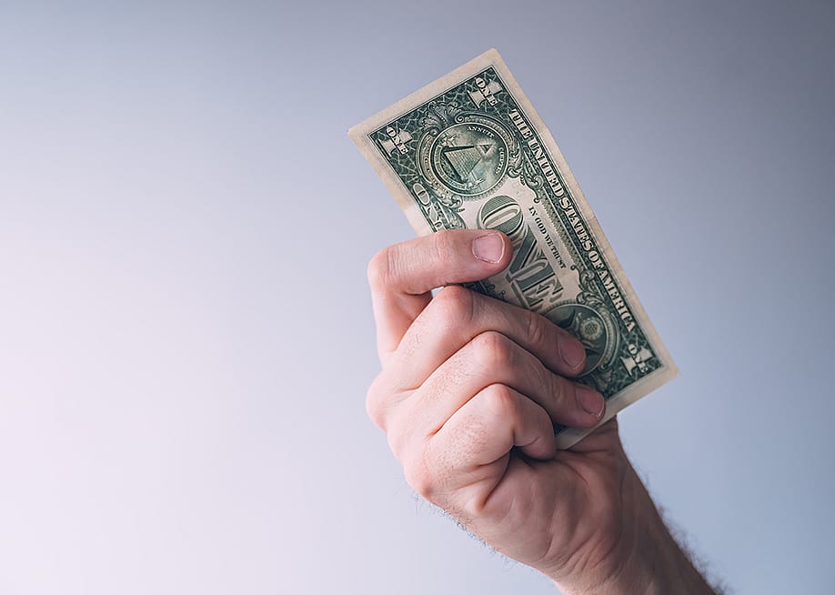 A focused photo of a person holding a one dollar bill. — Bits And Splits // Shutterstock