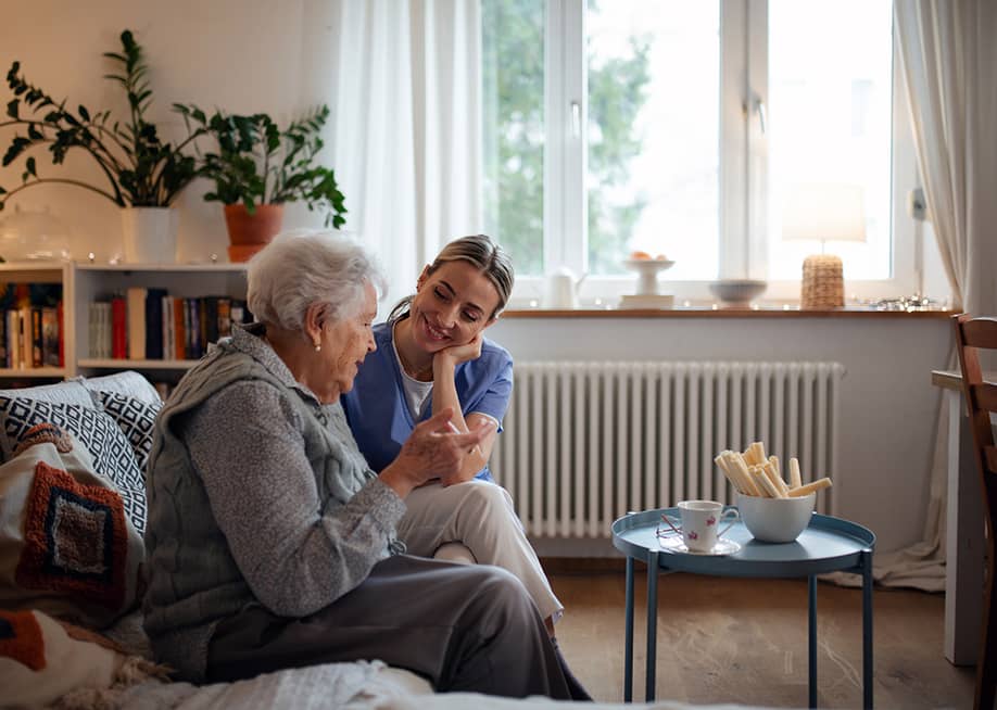 A senior woman accompanied by her caregiver at home. — Halfpoint // Shutterstock