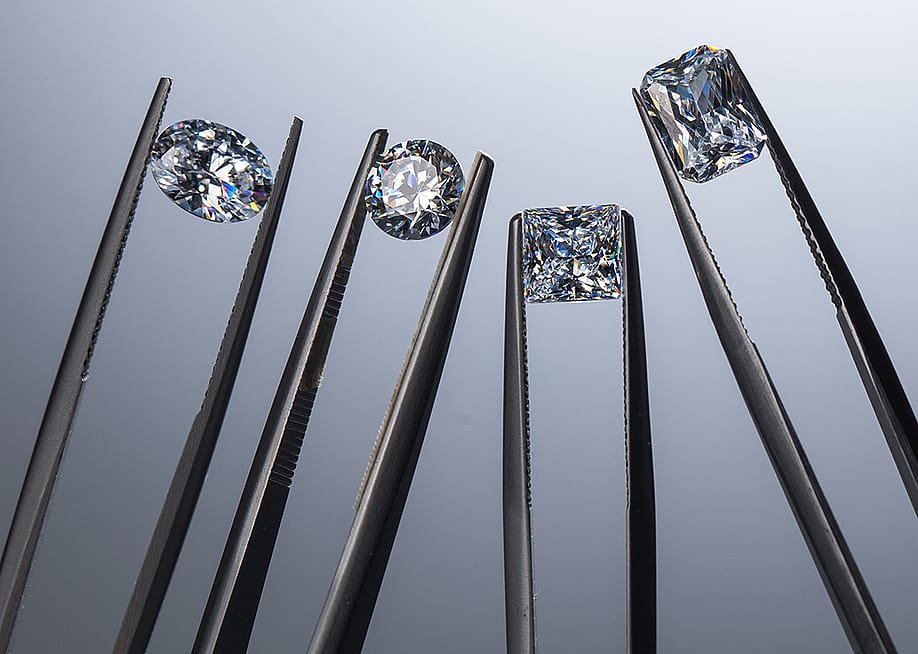 Close up of lab grown diamonds held by tweezers. — EgolenaHK // Shutterstock