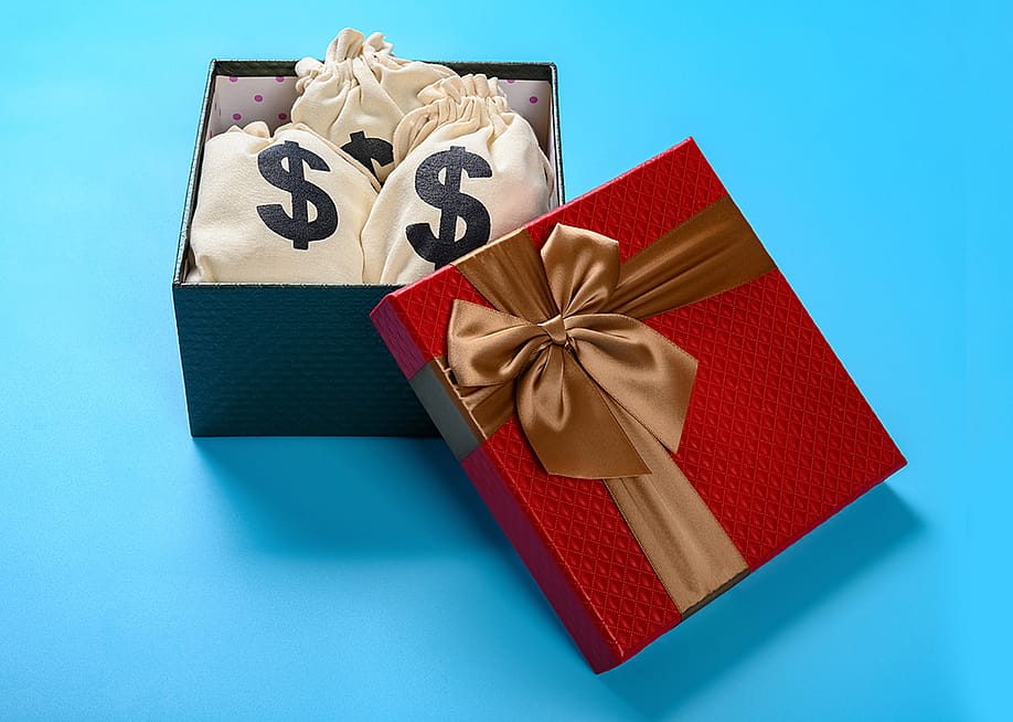 A gift box full of bags with dollar symbols. — Freer // Shutterstock