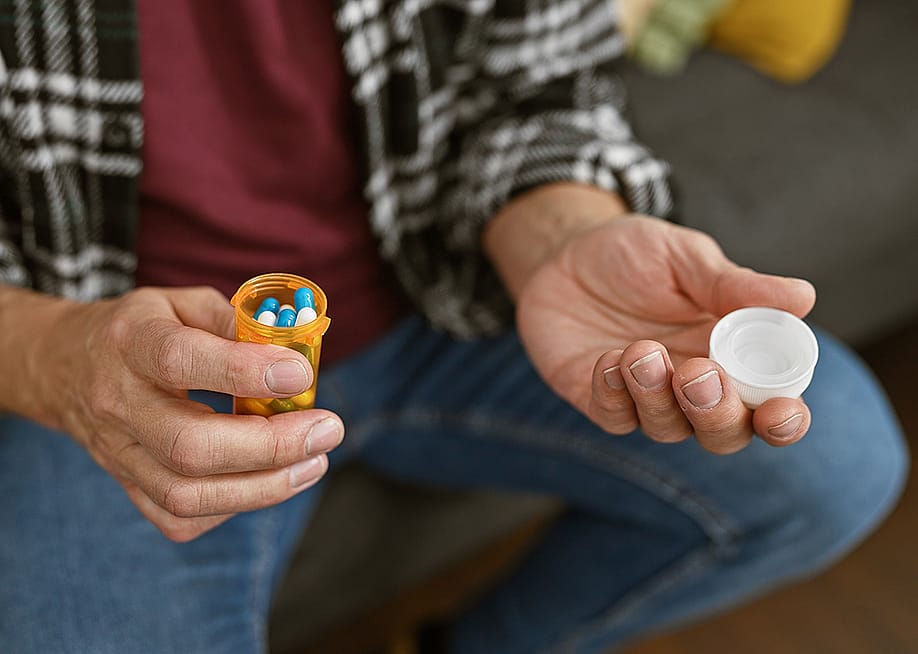 A person holding an opened medicine pill bottle. — Krakenimages.com // Shutterstock