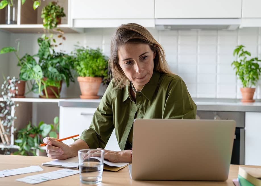A female homeowner focused on reviewing documents at home. — DimaBerlin // Shutterstock