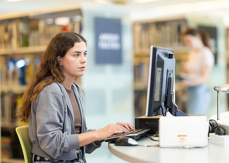 A female student using a computer at a university library. — BearFotos // Shutterstock