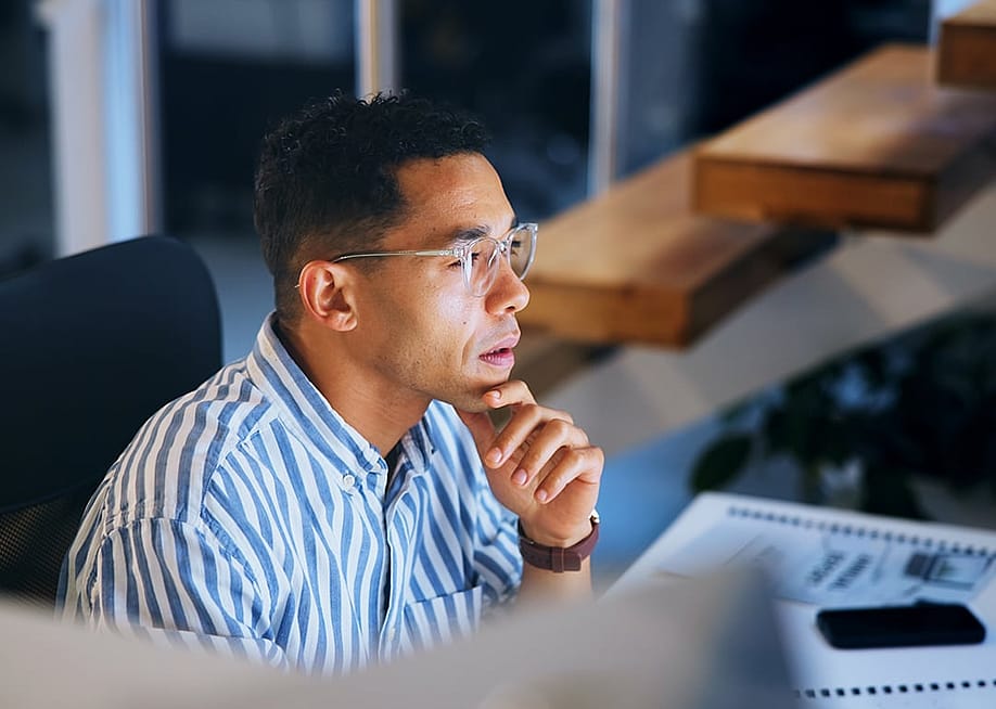 A focused businessman working at night in an office. — PeopleImages // Shutterstock