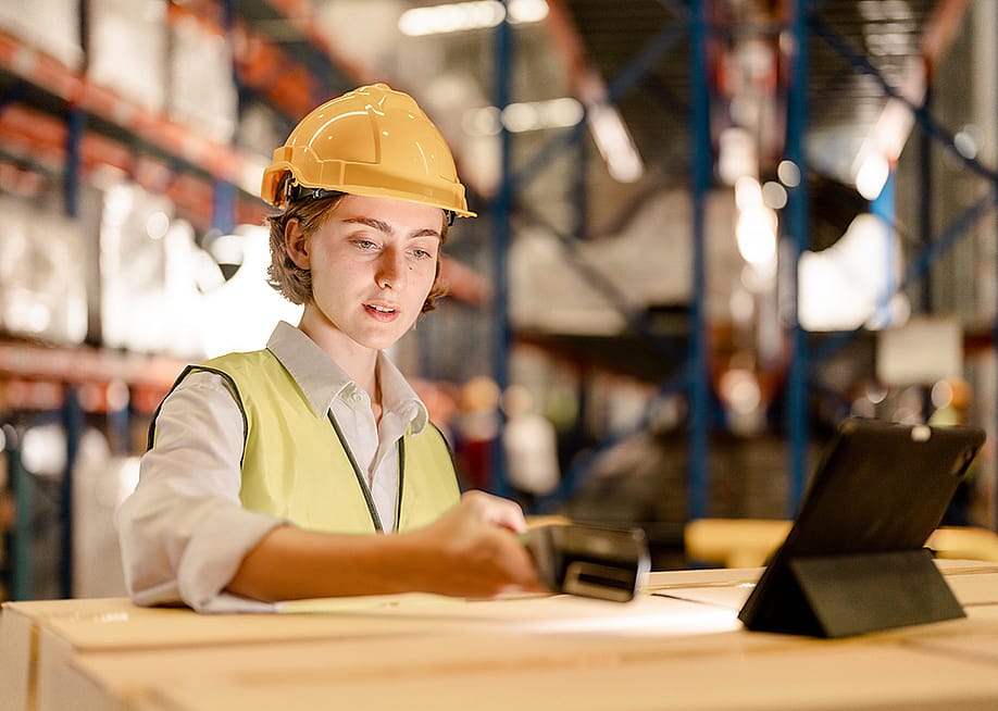 A female industrial staff in a safety suit working inside a warehouse. — ultramansk // Shutterstock