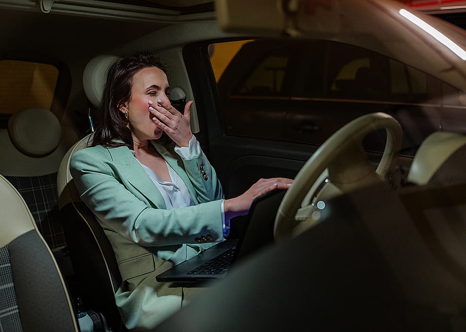 An employee yawning inside her car after work. — f.t.Photographer // Shutterstock