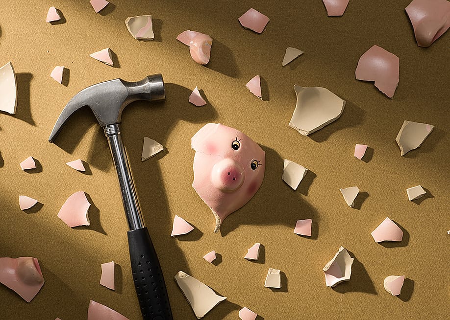 A broken piggy bank and a hammer on the floor. — Stokkete // Shutterstock