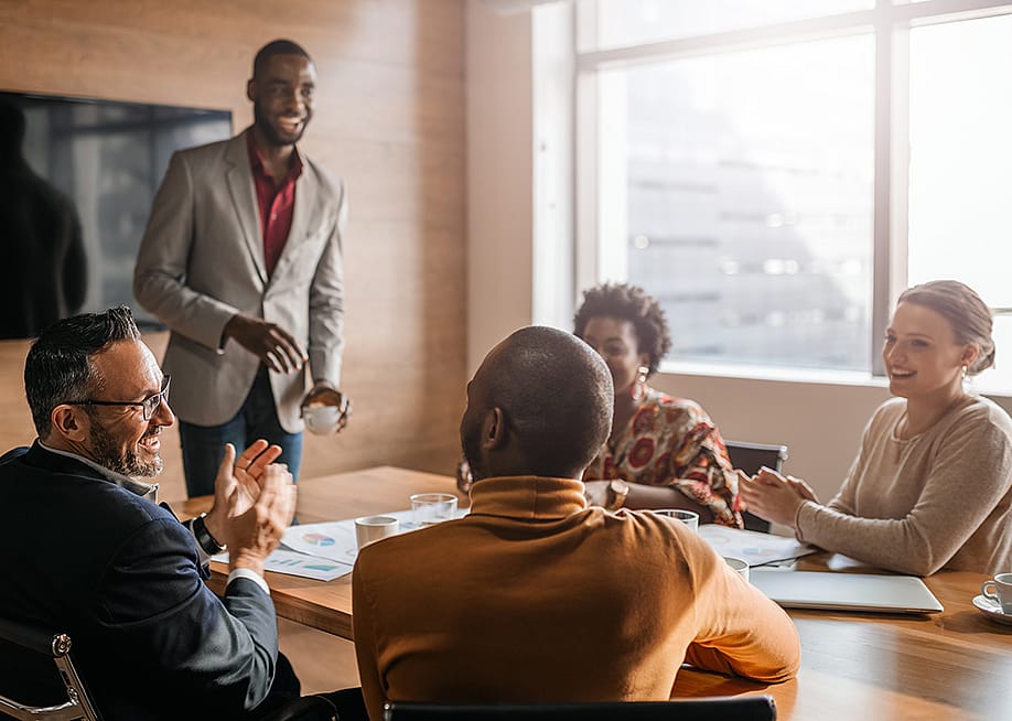 Coworkers enjoying a lighthearted moment during an office meeting. — Jono Erasmus // Shutterstock