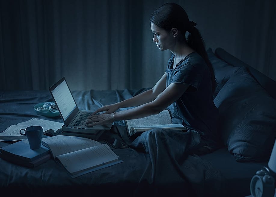 A student pulling an all-nighter for an exam in her bedroom. — Stock-Asso // Shutterstock