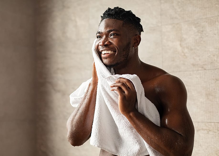 A person wiping his face with a towel after a shower. — Prostock-studio // Shutterstock