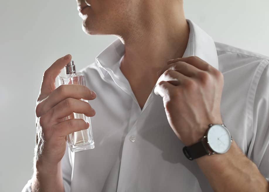 A close-up of a person applying a perfume in his neck. — New Africa // Shutterstock