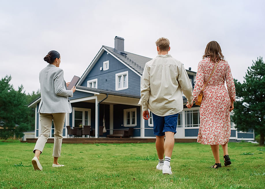 A young couple viewing a property for sale with an agent. — Gorodenkoff // Shutterstock