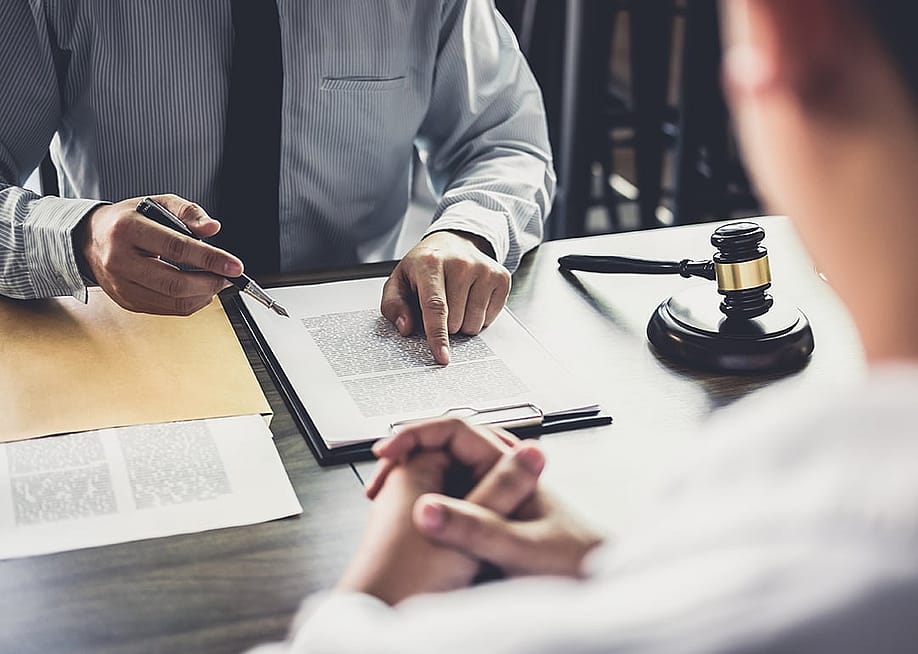 A lawyer consulting with his client and reviewing documents. — Freedomz // Shutterstock
