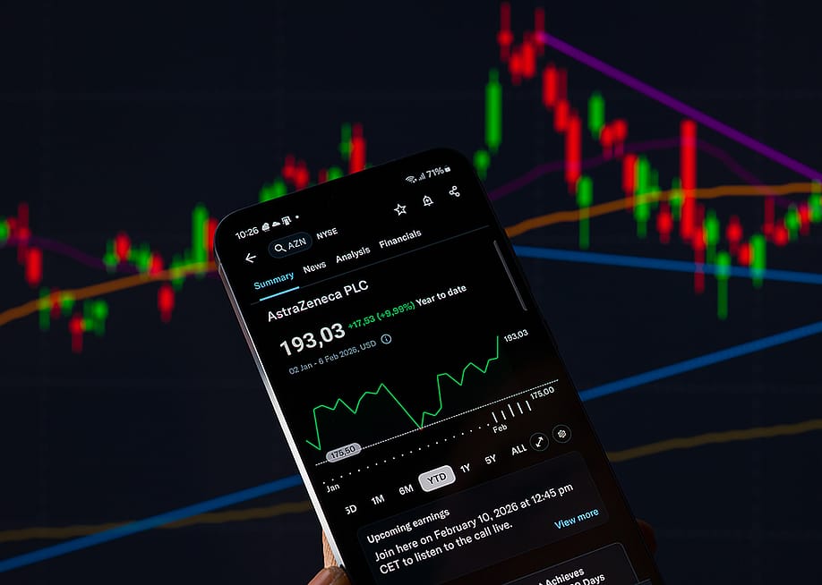 The AstraZeneca stock graph displayed on a mobile phone with other stock charts in the background. — Jonathan Raa // NurPhoto via Getty Images