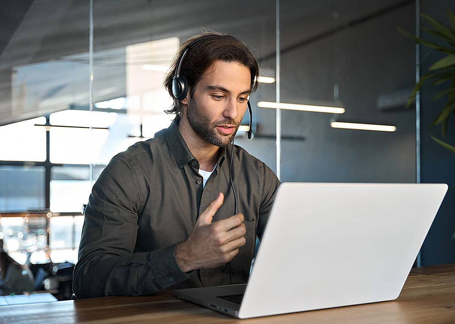 A male customer support service employee in an office working on a call with a client. — insta_photos // Shutterstock