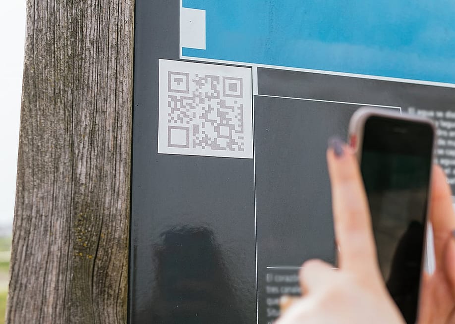 User scanning a QR code on a wall with a phone. — Miguel Paricio // Shutterstock