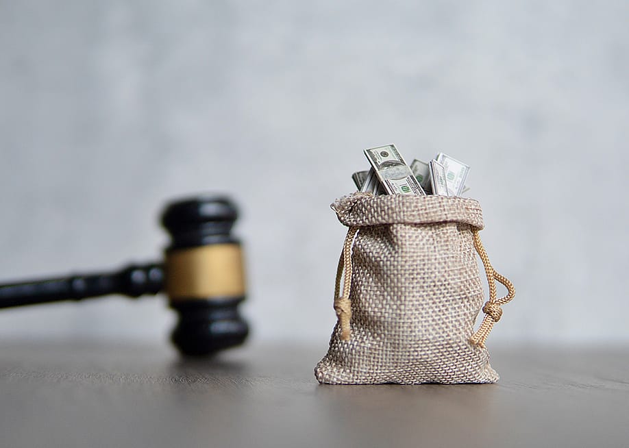 A small bag of money and a judge's gavel as a concept of penalty in lawsuit. — izzuanroslan // Shutterstock