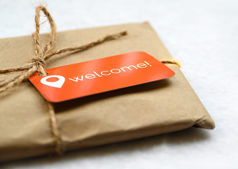 A brown package with an orange welcome tag. — Cindy Bird // Shutterstock