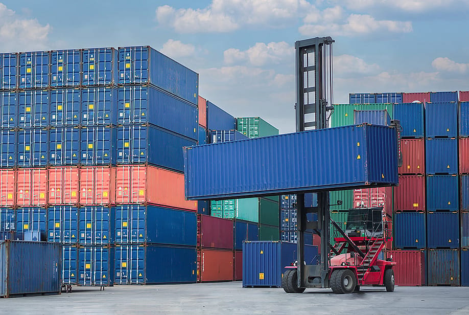 A forklift lifting a container van in a shipping yard. — Shutter z // Shutterstock