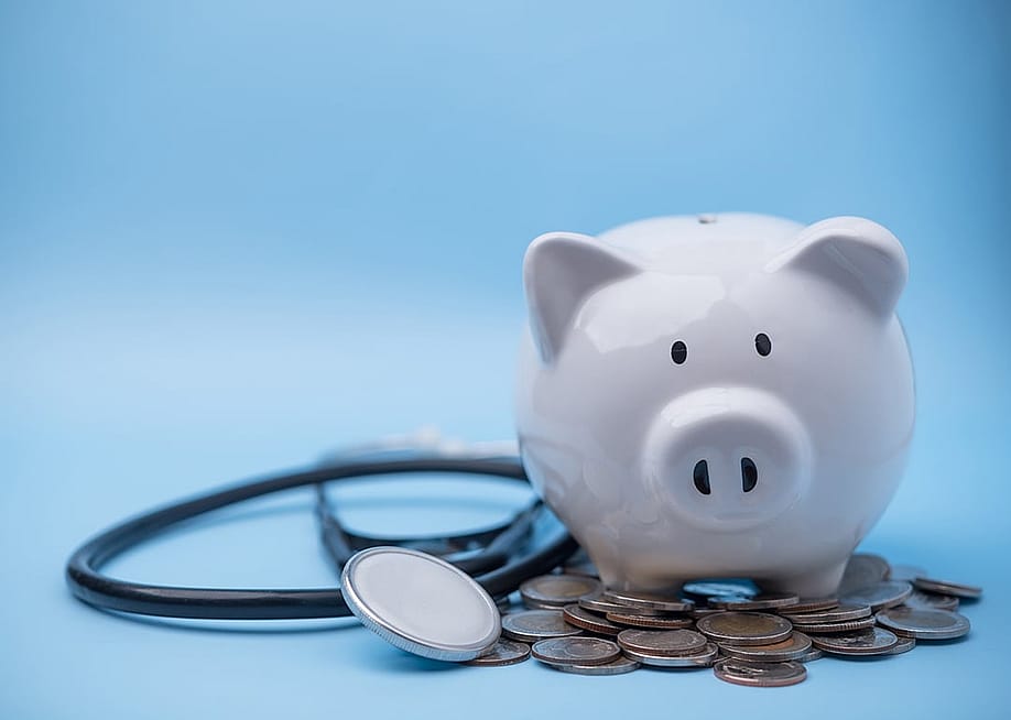A piggy bank with coins and a stethoscope. — khunkornStudio // Shutterstock