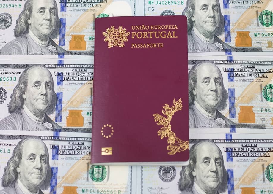 A Portuguese passport on top of one hundred U.S. dollar bills. — Gabriel_Ramos // Shutterstock