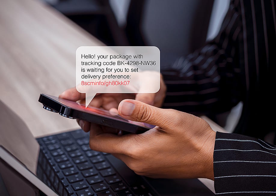 Person using phone with an illustration of an SMS bubble showing potential scam with phishing link. — tete_escape // Shutterstock