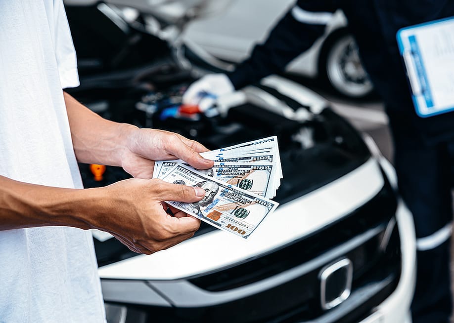 Customer pays with cash to the car mechanic after a service. — Thx4Stock team // Shutterstock