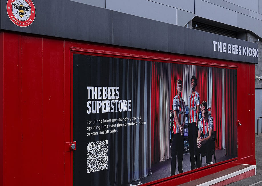A Brentford Football Club merchandise kiosk promoting The Bees superstore with a QR code in London, United Kingdom. — 4kclips // Shutterstock