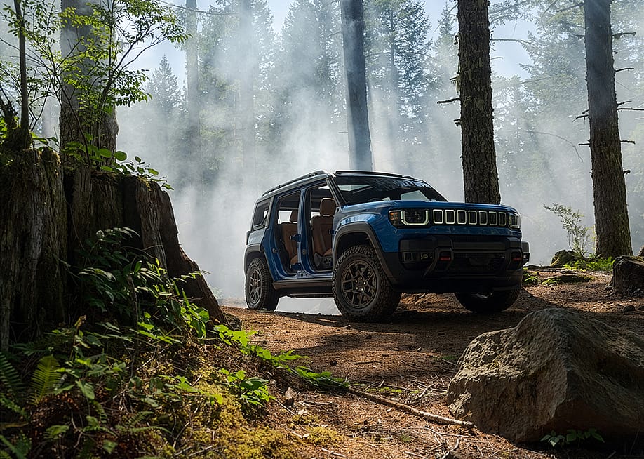 Low angle view of a Blue Jeep Recon Moab parked in a forest with mist rising in the background. — Stellantis Media