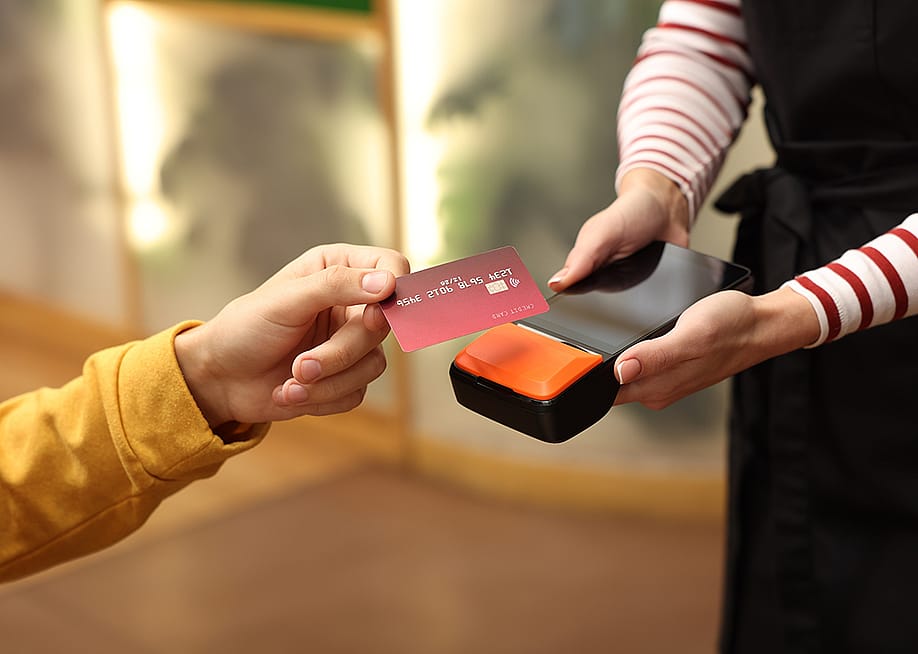 A person paying with a credit card payment machine held by a cafe staff. — New Africa // Shutterstock