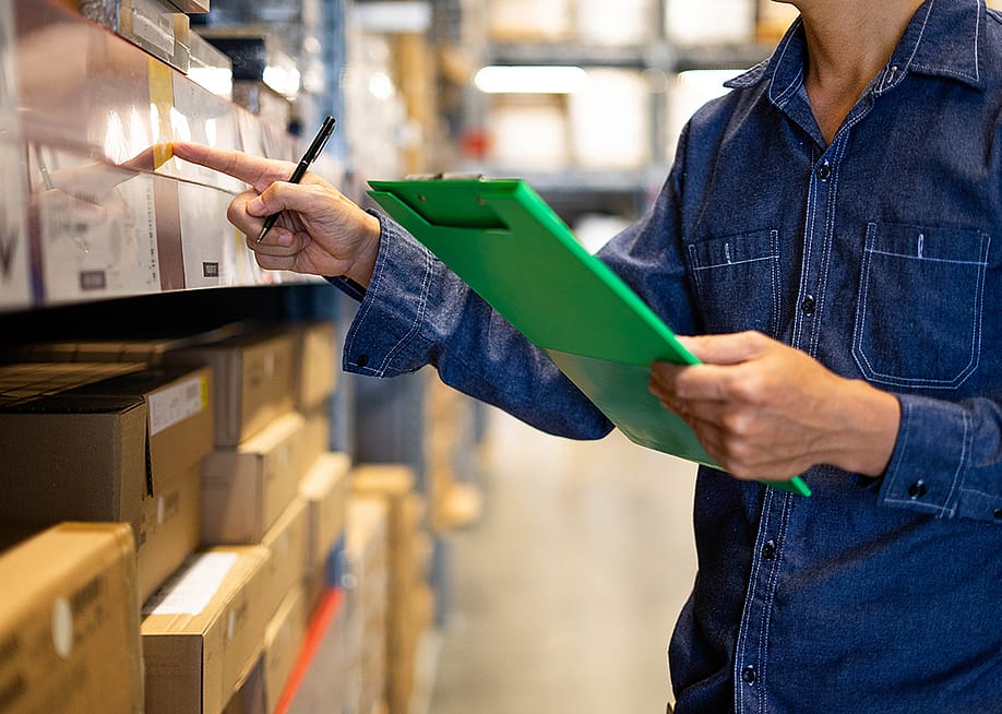 A factory assistant checking stocks for an inventory at a warehouse. — thebigland // Shutterstock