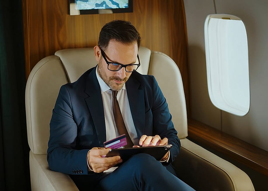A business executive shopping online while traveling from a private jet's cabin. — Videophilia // Shutterstock