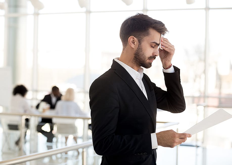 A business employee sweating and feeling nervous before speaking to an audience. — fizkes // Shutterstock