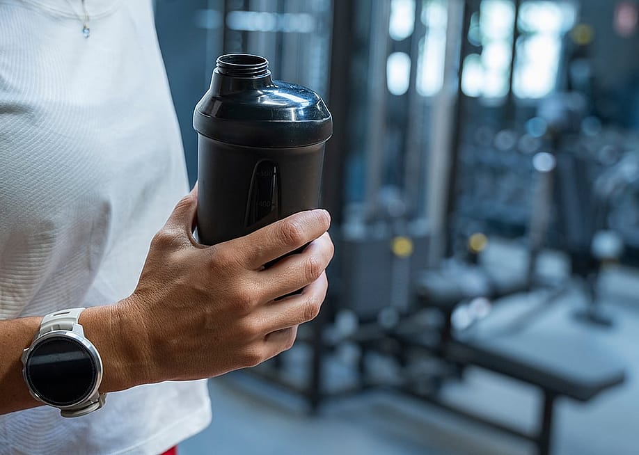 A person holding a water bottle during her workout in a gym. — Marta Masdeu Navarro // Shutterstock