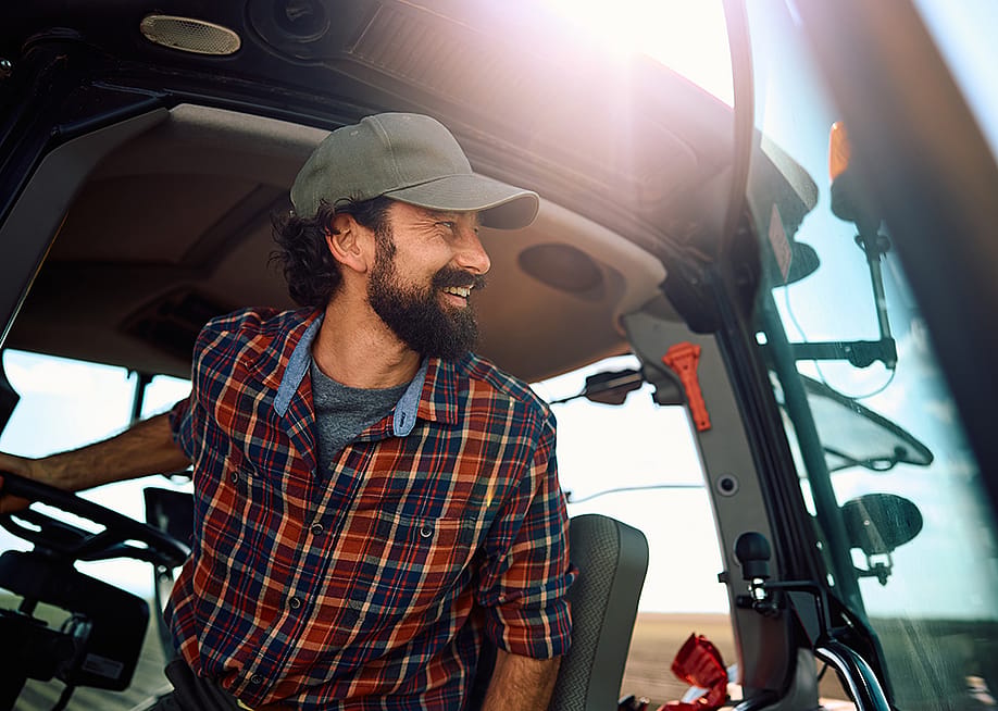 A farm worker in a tractor looking at an agricultural field. — Drazen Zigic // Shutterstock