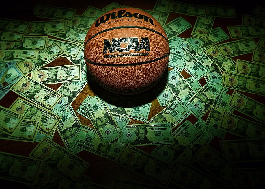 An NCAA Final Four Edition basketball surrounded by banknotes. — zimmytws // Shutterstock