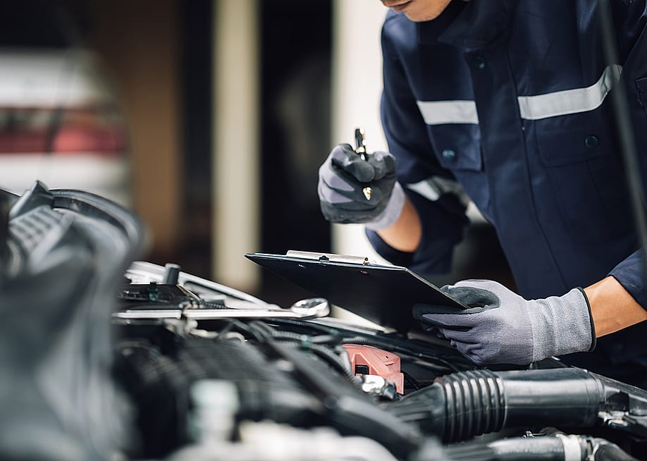 A car mechanic doing a checklist while looking at an engine. — Kunakorn Rassadornyindee // Shutterstock
