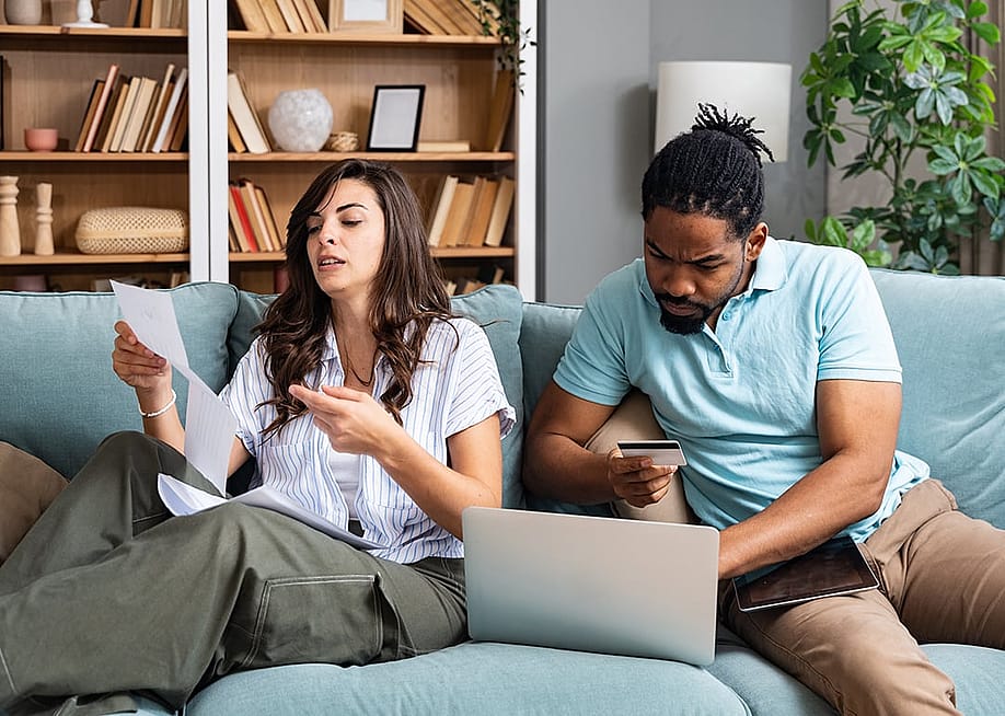 A couple at home stressfully reviewing household bills. — Srdjan Randjelovic // Shutterstock